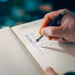 Person checking off items in a hand-written checklist