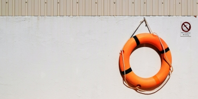 Orange life preserver hanging on a white wall