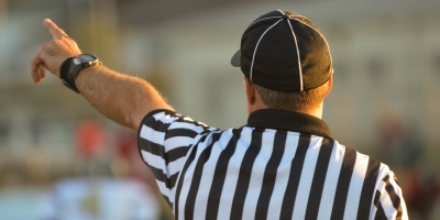 Sports referee pointing with his arm outstretched, seen from the back